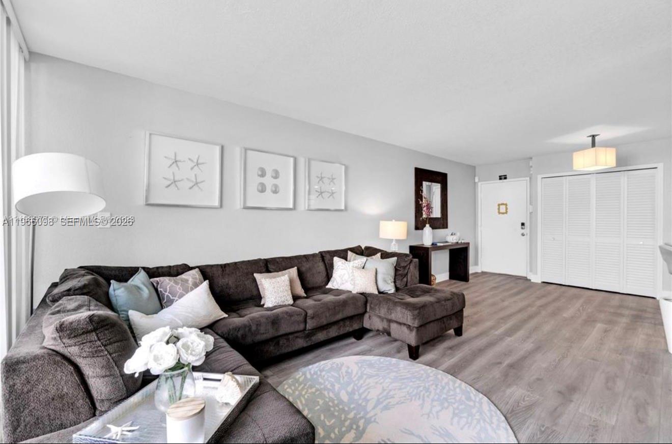 A living room features a large gray sectional sofa, light wood flooring, and framed artwork — 830 NW 87th Ave # 303, Miami FL 33172, MIAMI, FL