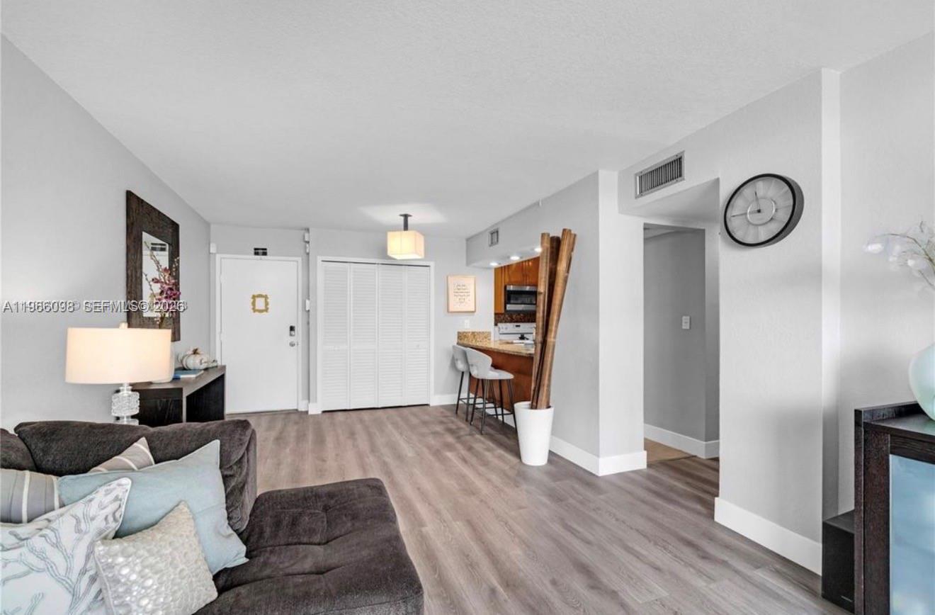 A living room with light wood floors, a breakfast bar, and a white front door — 830 NW 87th Ave # 303, Miami FL 33172, MIAMI, FL