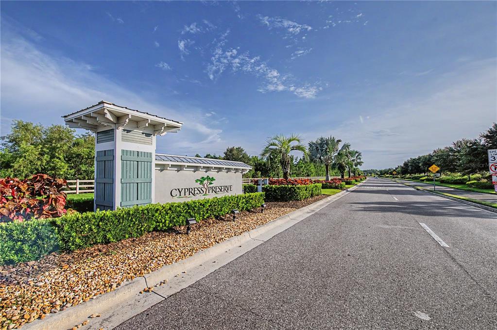 A stone monument sign for Cypress Preserve stands beside a paved road with landscaping — 10331 HERON HIDEAWAY LOOP, LAND O LAKES, FL