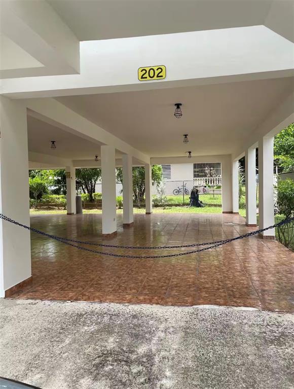 A covered parking area with tiled flooring, white support pillars, and a chain barrier — Apt 202 MANUEL GUILLOTY / LIBREVATO MONTALVO UNIT 202, CABO ROJO, PR