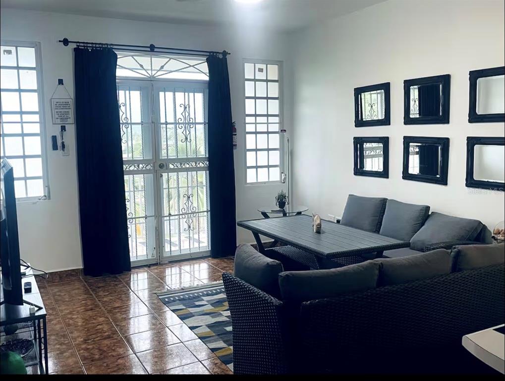 A living room features dark wicker furniture, a patterned rug, and black-framed wall mirrors — Apt 202 MANUEL GUILLOTY / LIBREVATO MONTALVO UNIT 202, CABO ROJO, PR