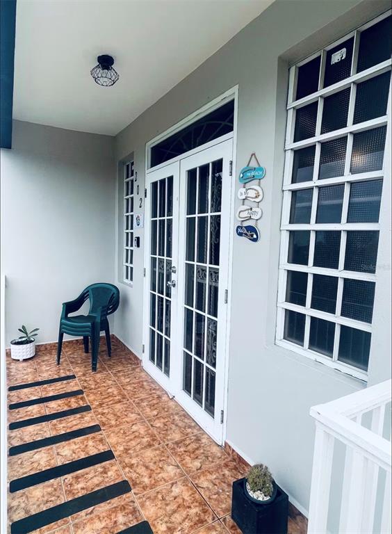 A covered porch features tiled flooring, a green plastic chair, and a white double door — Apt 202 MANUEL GUILLOTY / LIBREVATO MONTALVO UNIT 202, CABO ROJO, PR