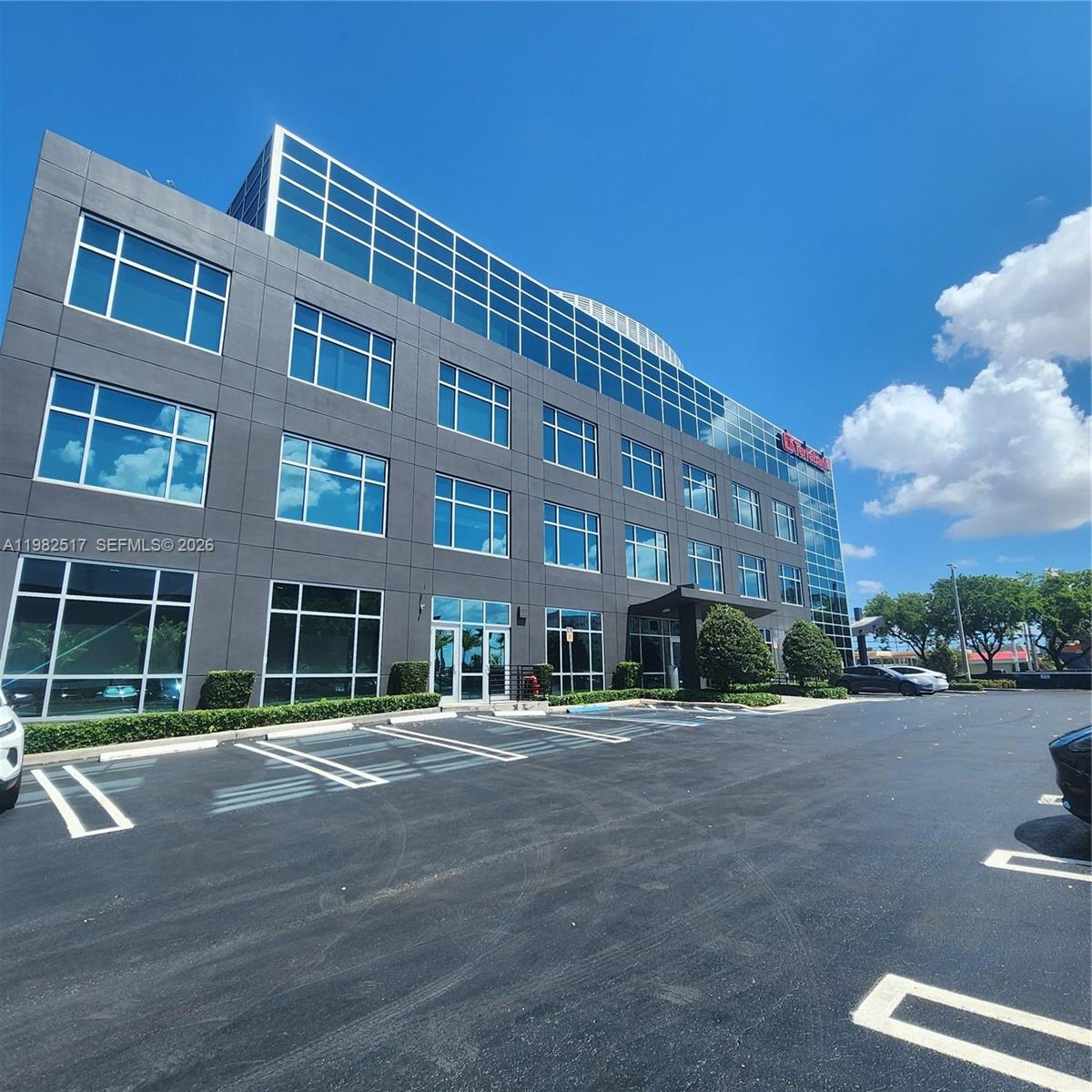 A modern, multi-story office building with a dark gray facade and large glass windows — 2500 NW 107th Ave # 400, Doral FL 33172, DORAL, FL