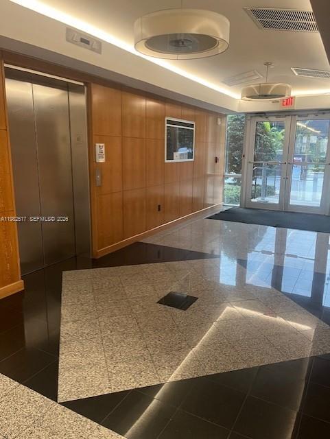 A lobby features wood-paneled walls, a stainless steel elevator, and a patterned tile floor — 2500 NW 107th Ave # 400, Doral FL 33172, DORAL, FL