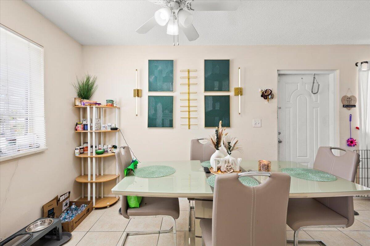 A dining room features a glass-top table, four chairs, a corner shelf, and wall art — 1905 Lake Worth Road, FL 33461, FL