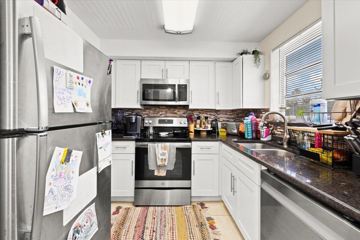 A kitchen with white cabinets, dark granite countertops, stainless steel appliances, and a tiled backsplash — 1905 Lake Worth Road, FL 33461, FL