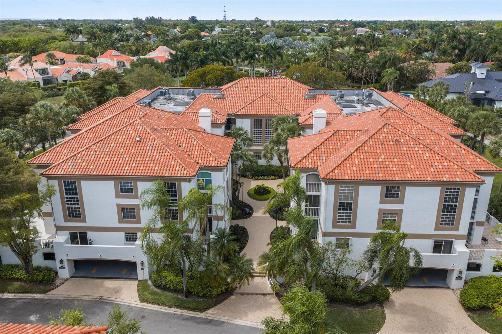 An aerial view of a multi-story apartment building with a terracotta tile roof and courtyard — 7370 Orangewood Lane # 302, Boca Raton FL 33433, BOCA RATON, FL