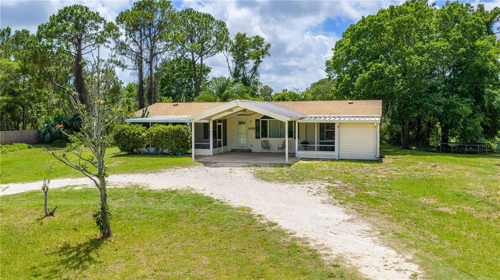 A single-story house with light siding, a shingled roof, and a covered front porch — 1055 ACEE DRIVE, NEW SMYRNA BEACH, FL