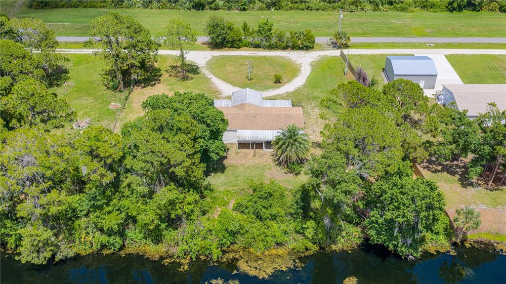 An aerial view shows a house with a brown roof situated on a waterfront lot — 1055 ACEE DRIVE, NEW SMYRNA BEACH, FL