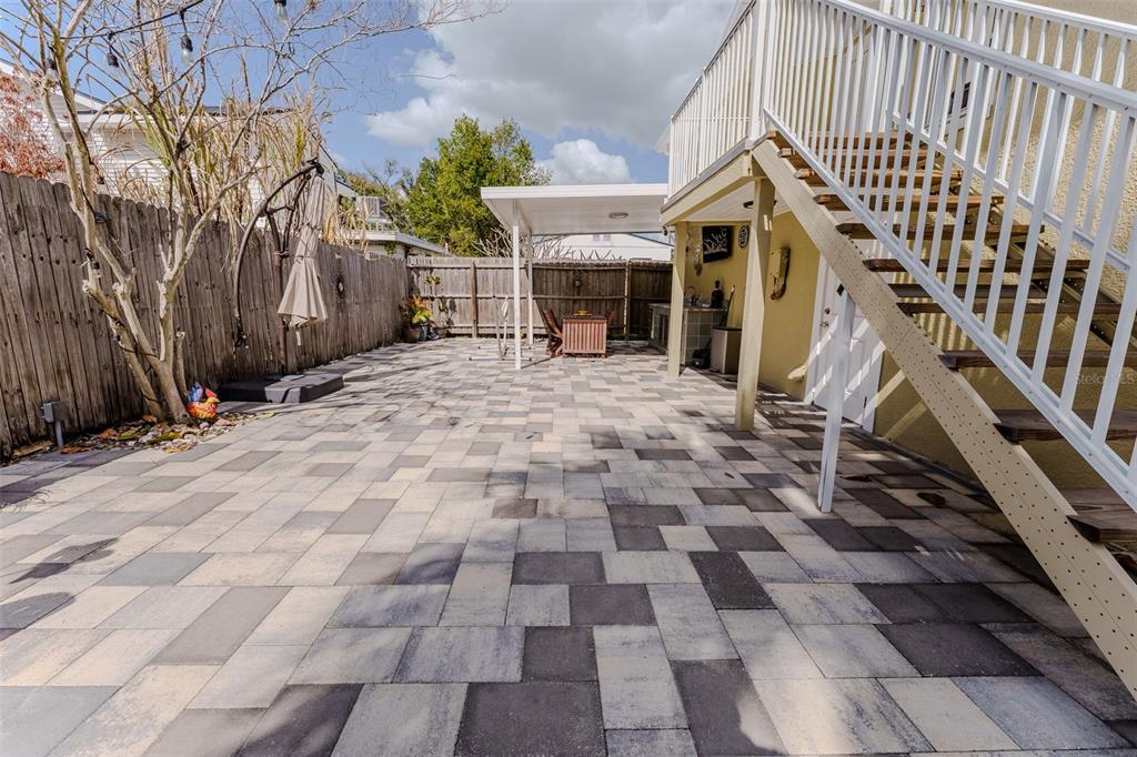 A paved backyard patio features a covered seating area, an outdoor kitchen, and exterior stairs — 203 W CREST AVENUE, TAMPA, FL