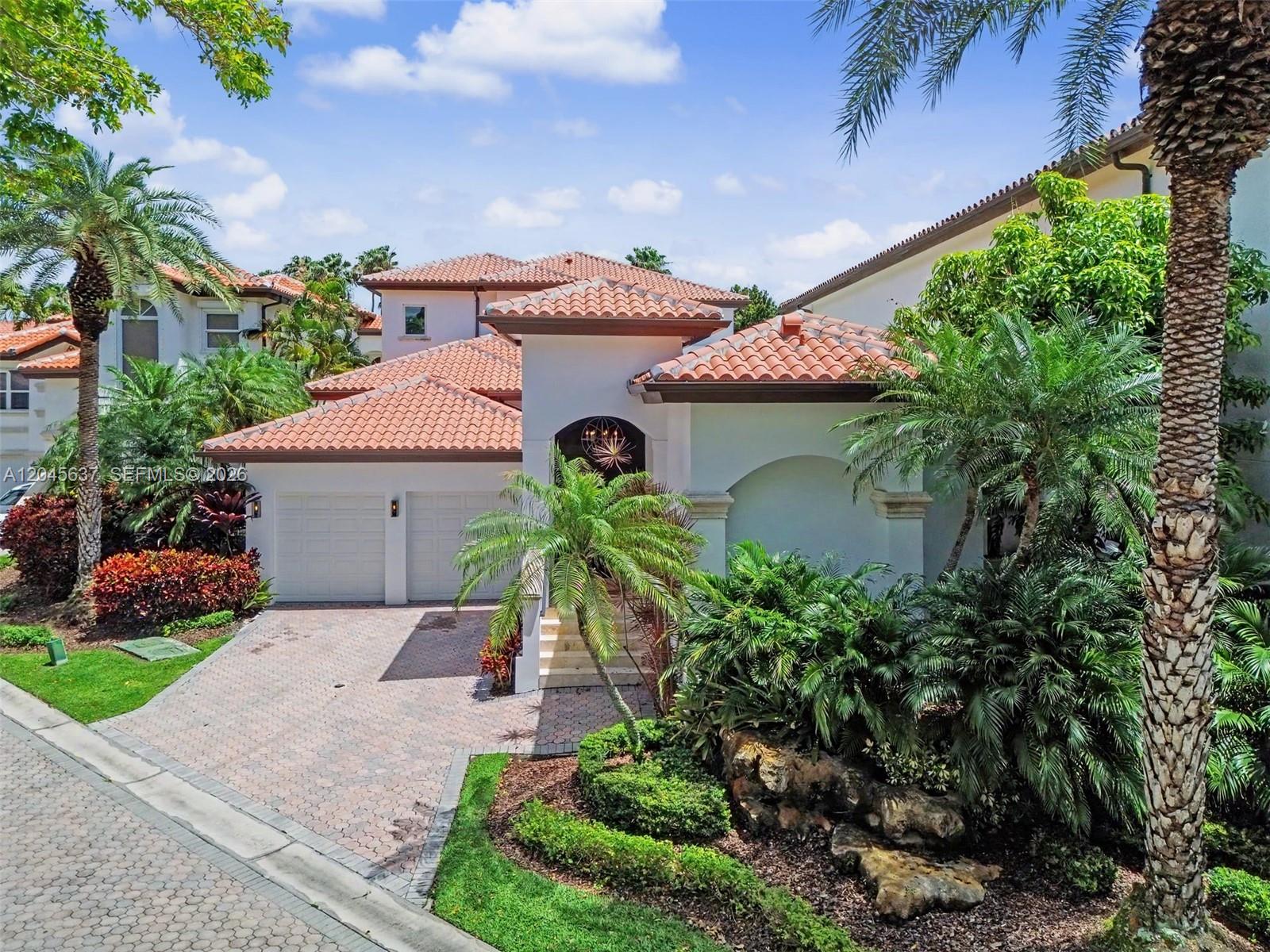 An exterior view of a two-story Mediterranean-style house with a tile roof and paved driveway — 13689 Deering Bay Dr, Coral Gables FL 33158, CORAL GABLES, FL