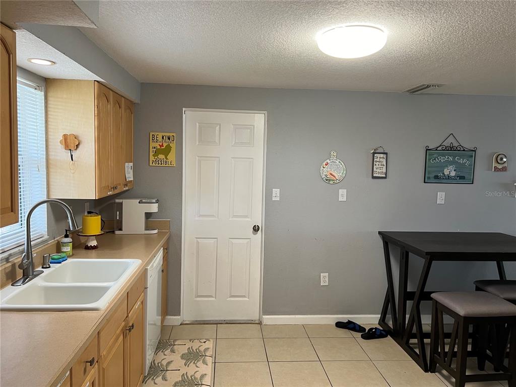 A kitchen features light wood cabinets, a white double sink, and a small dining area — 705 CRESTVIEW CIRCLE NW, PORT CHARLOTTE, FL
