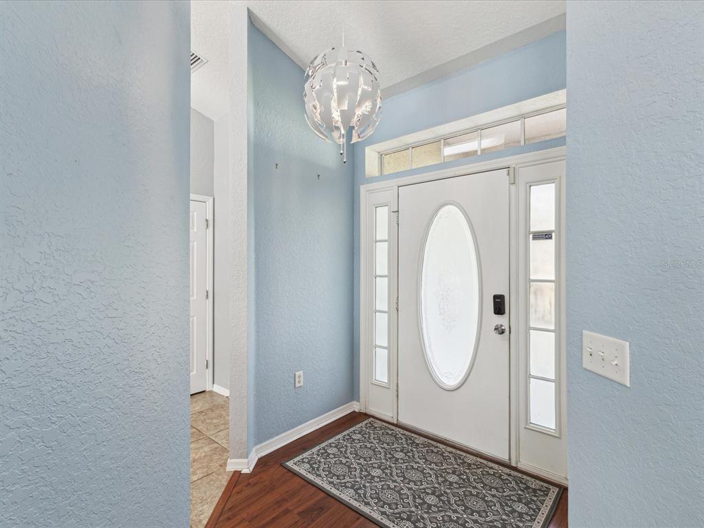 A foyer with light blue walls, a modern pendant light, and a white front door — 6076 SHIPROCK AVENUE, SPRING HILL, FL
