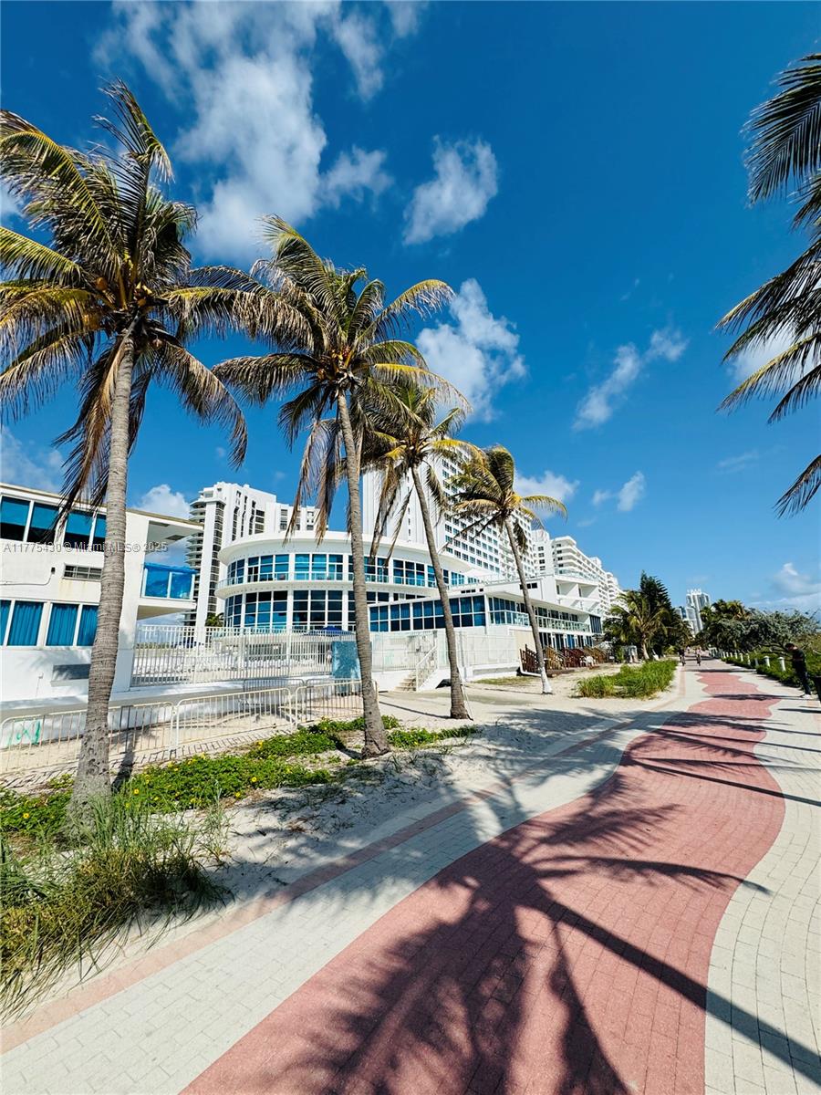 A paved walkway runs alongside a sandy beach with palm trees and a large building — 5445 Collins Ave # 1520, Miami Beach FL 33140, MIAMI BEACH, FL