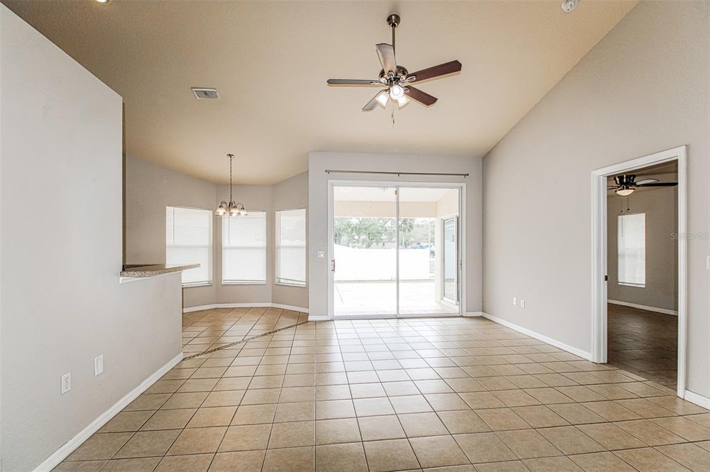 A living room with tile floors, a ceiling fan, and sliding glass doors to a patio — 3428 TOMAHAWK AVENUE, SPRING HILL, FL