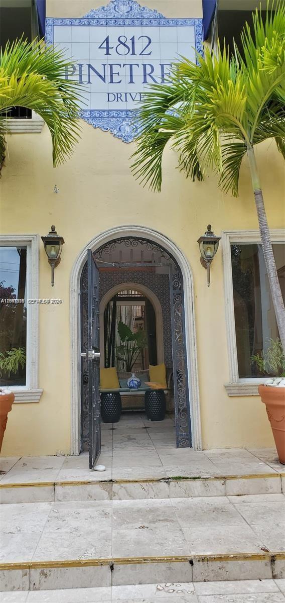 The exterior entrance features an arched doorway, decorative tile signage, and two flanking palm trees — 4812 Pine Tree Dr # 201, Miami Beach FL 33140, MIAMI BEACH, FL