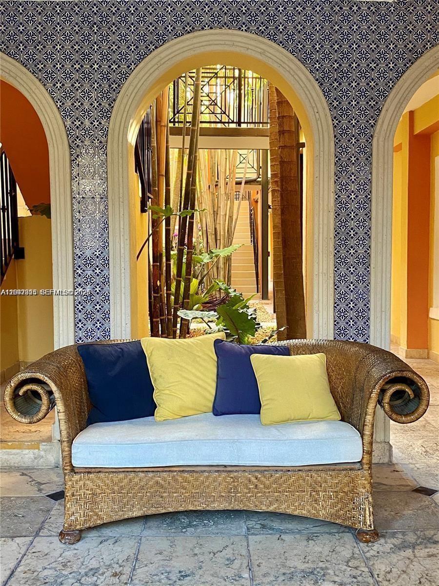 A wicker sofa sits in front of an arched entryway with blue patterned tile walls — 4812 Pine Tree Dr # 201, Miami Beach FL 33140, MIAMI BEACH, FL