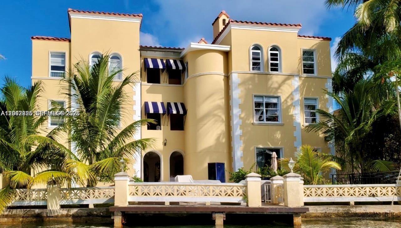 A three-story yellow stucco house with a waterfront deck and palm trees — 4812 Pine Tree Dr # 201, Miami Beach FL 33140, MIAMI BEACH, FL