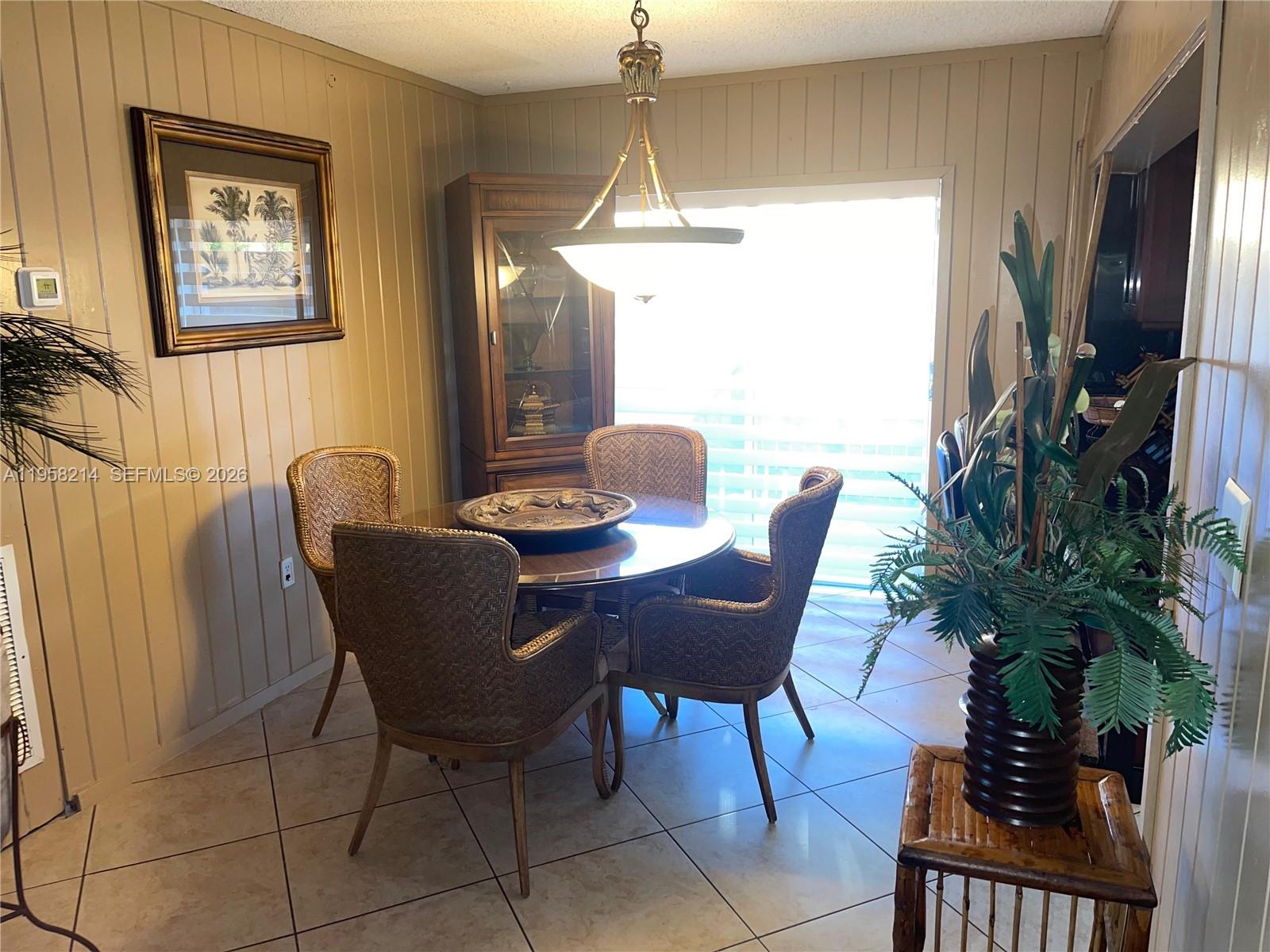 A dining room features a round table with four wicker chairs, wood paneling, and tile flooring — 6510 Park St, Hollywood FL 33024, HOLLYWOOD, FL