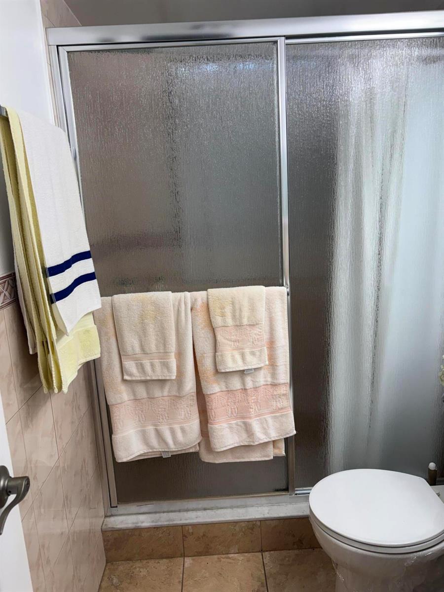 A bathroom features a glass shower door with towels hanging over the handle and frame — 25 Kent B, West Palm Beach FL 33417, WEST PALM BEACH, FL