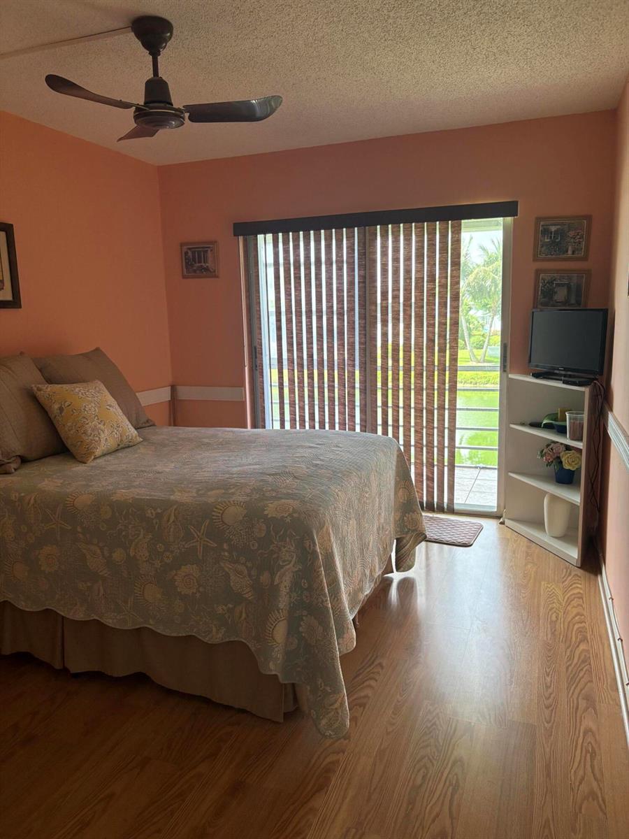 A bedroom with peach walls, a bed, a ceiling fan, and a sliding glass door — 25 Kent B, West Palm Beach FL 33417, WEST PALM BEACH, FL