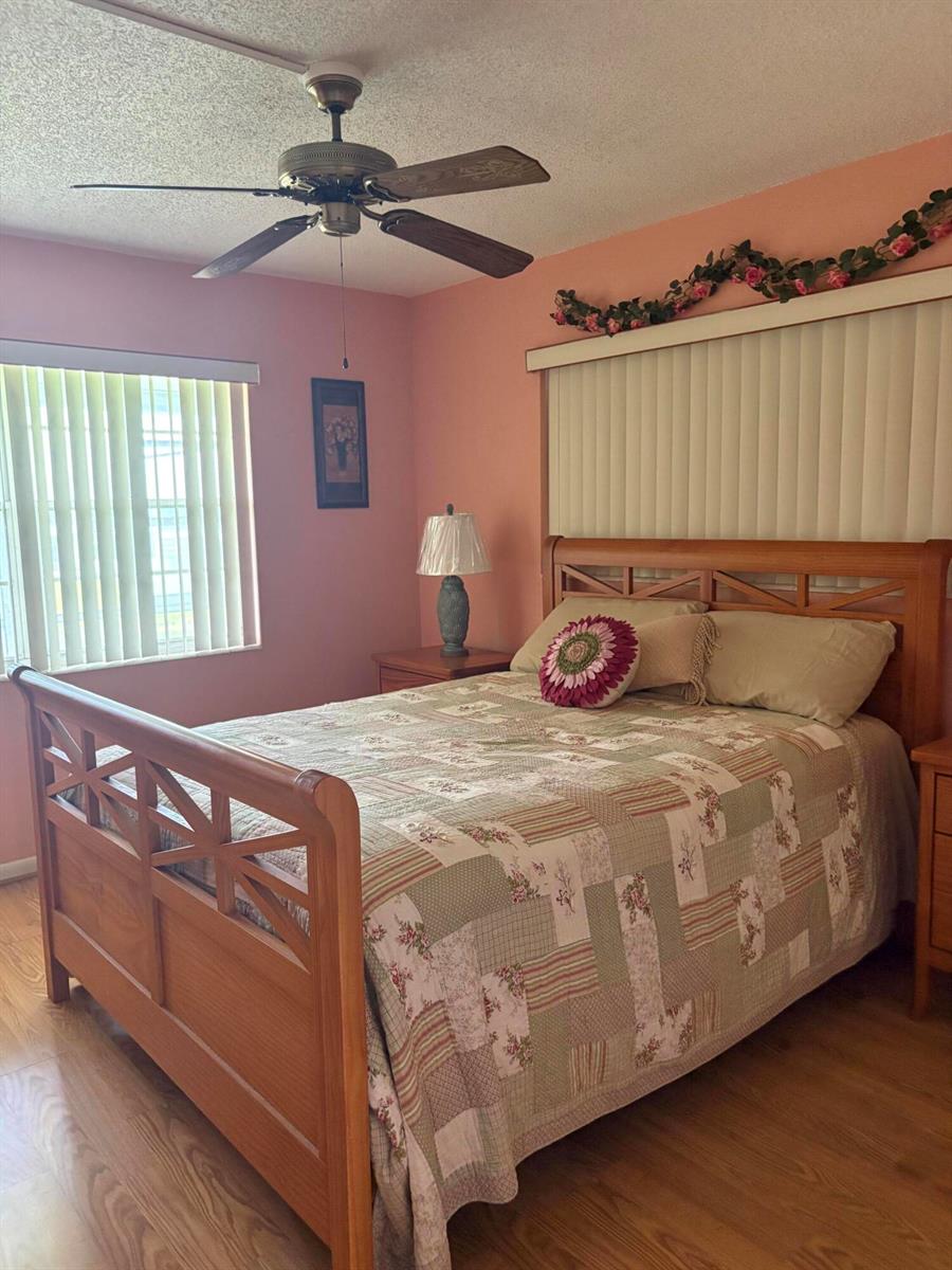 A bedroom features a wooden bed frame, a patterned quilt, and pink walls — 25 Kent B, West Palm Beach FL 33417, WEST PALM BEACH, FL