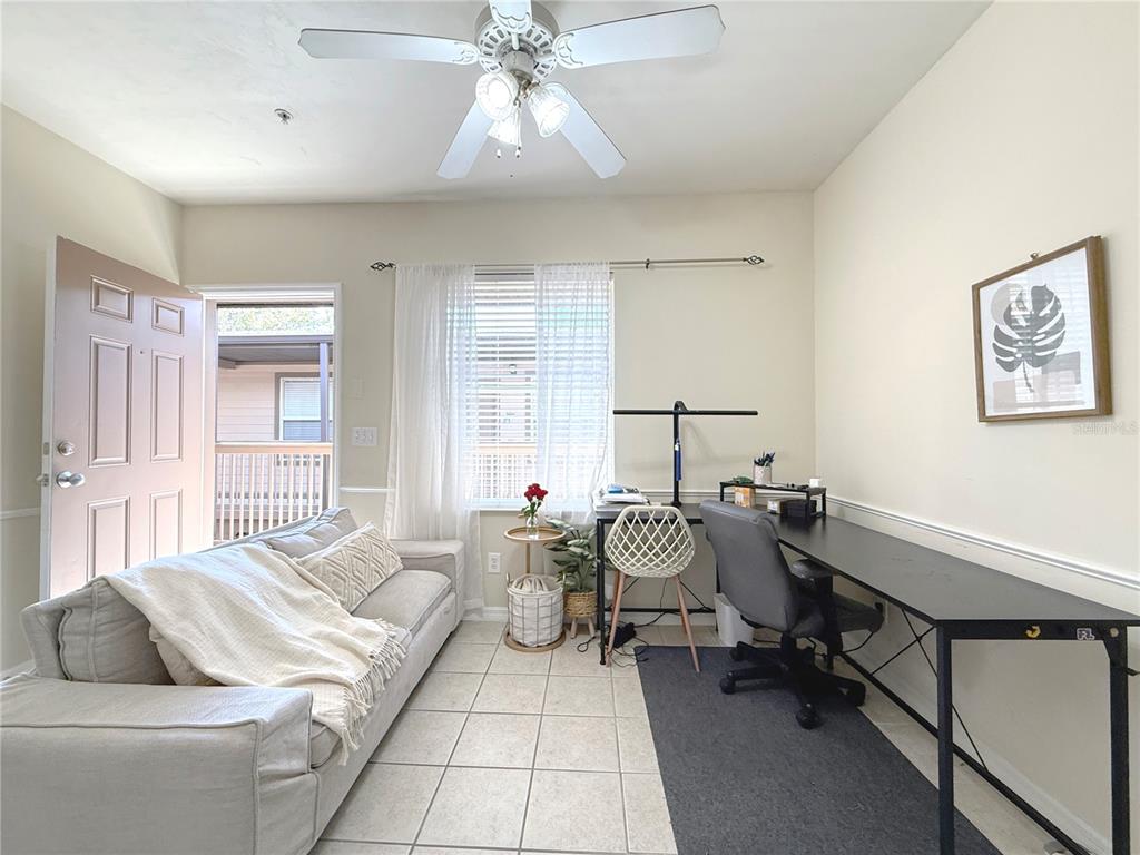 A living room with a sofa, a long desk, tile flooring, and a ceiling fan — 1220 SW 1ST AVENUE UNIT 303, GAINESVILLE, FL
