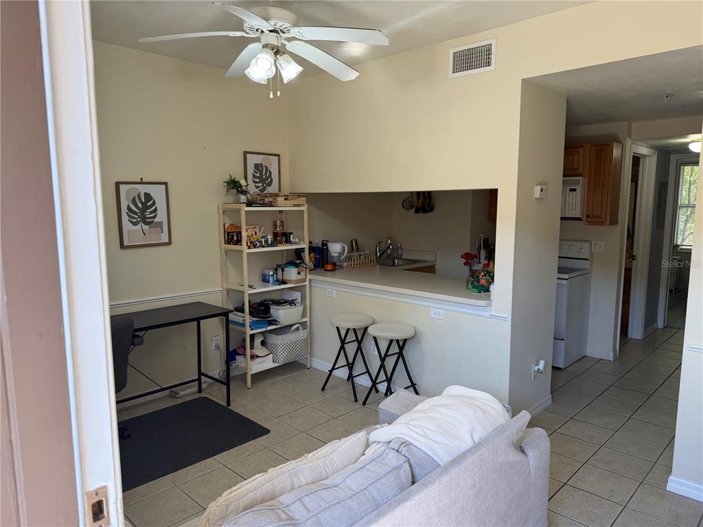 A living area features a desk, shelving, a breakfast bar with stools, and tile flooring — 1220 SW 1ST AVENUE UNIT 303, GAINESVILLE, FL