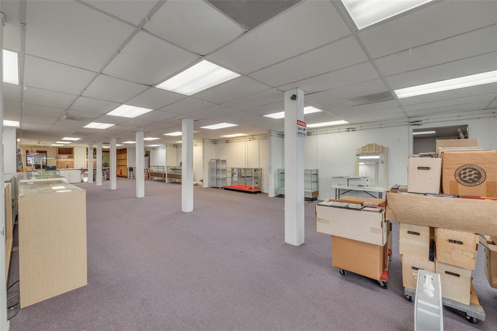 An empty commercial space features a drop ceiling, fluorescent lighting, carpeted floors, and support columns — 2865 E BAY DRIVE, LARGO, FL