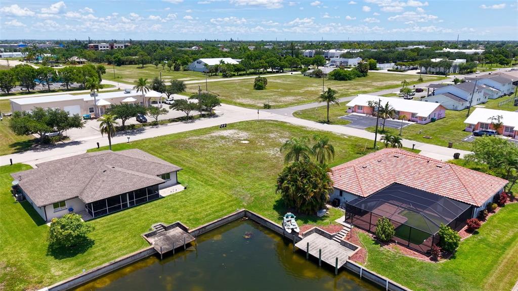 An aerial view shows two houses with screened lanais situated along a canal — 304 SW 3RD PLACE, CAPE CORAL, FL