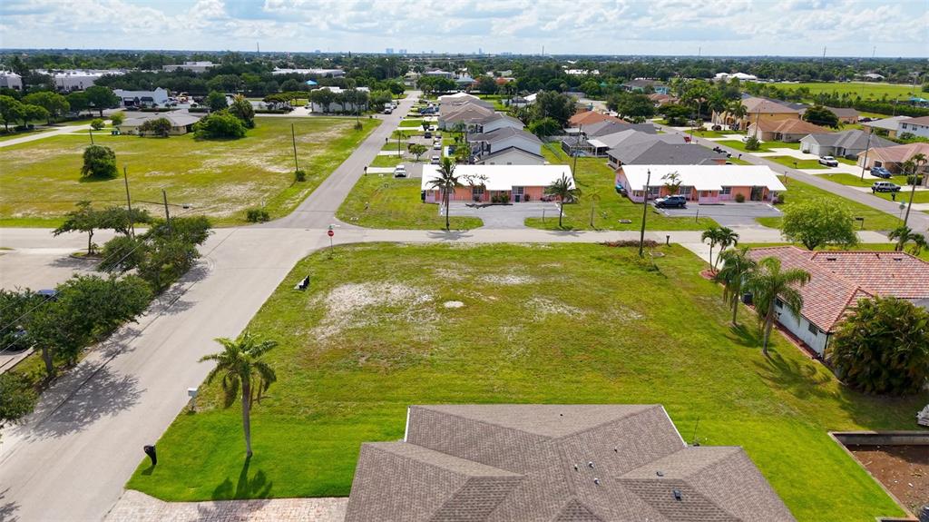 An aerial view shows a vacant grassy lot situated between a residential street and houses — 304 SW 3RD PLACE, CAPE CORAL, FL