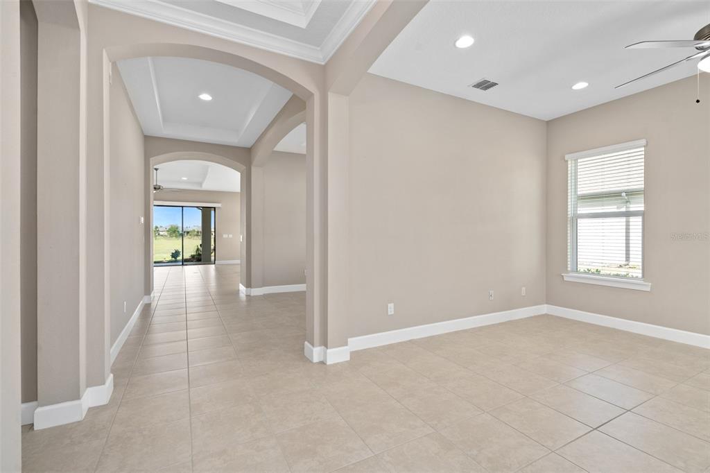 A bright room with beige tile floors, arched entryways, and a view of a backyard — 1222 ZEEK RIDGE STREET, CLERMONT, FL