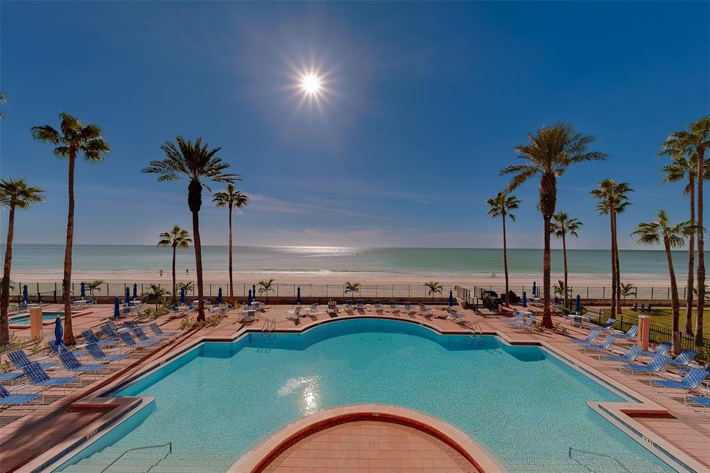 An outdoor swimming pool overlooks a sandy beach and the ocean under a bright sun — 16550 GULF BOULEVARD UNIT 342, NORTH REDINGTON BEACH, FL
