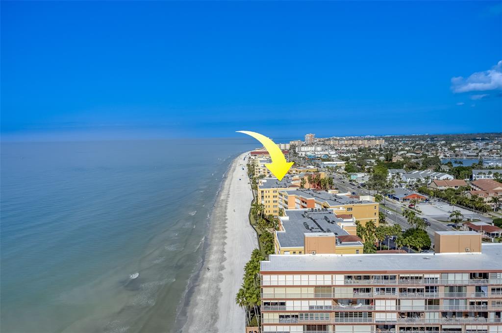 An aerial view shows a yellow beachfront condominium complex along a sandy coastline — 16550 GULF BOULEVARD UNIT 342, NORTH REDINGTON BEACH, FL