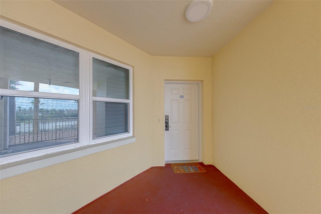 A covered entryway features a white front door, a large window, and red flooring — 16550 GULF BOULEVARD UNIT 342, NORTH REDINGTON BEACH, FL