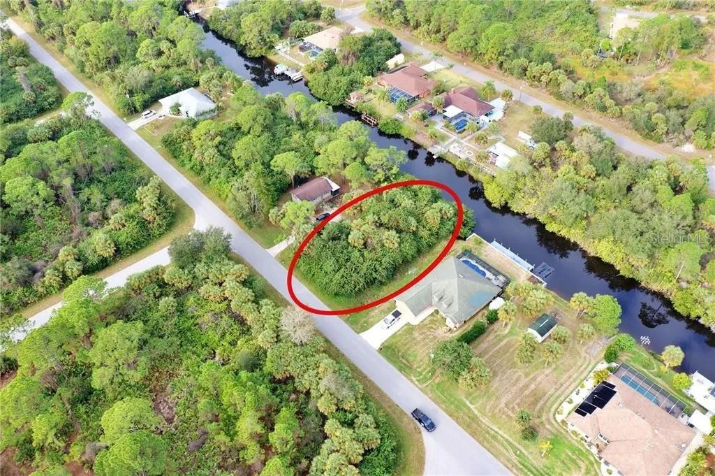 An aerial view shows a vacant, tree-covered lot outlined in red next to a canal — 369 CHESHIRE STREET, PORT CHARLOTTE, FL