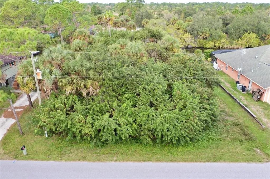 An aerial view of a heavily wooded, undeveloped residential lot situated between two houses — 369 CHESHIRE STREET, PORT CHARLOTTE, FL
