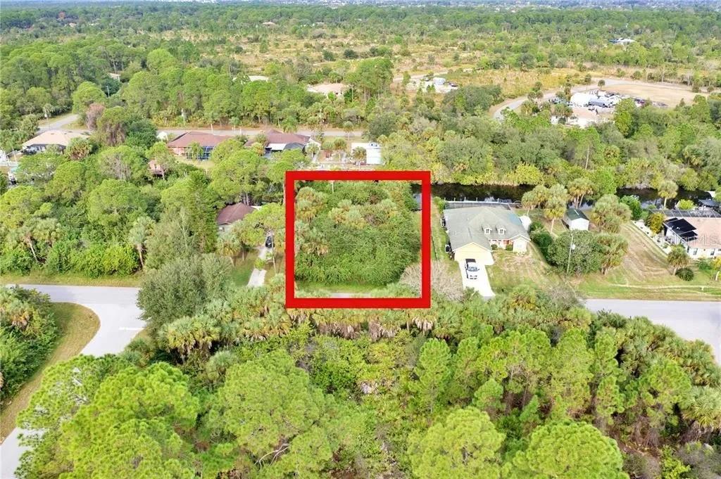 An aerial view shows a vacant, tree-covered lot outlined in red next to a house — 369 CHESHIRE STREET, PORT CHARLOTTE, FL