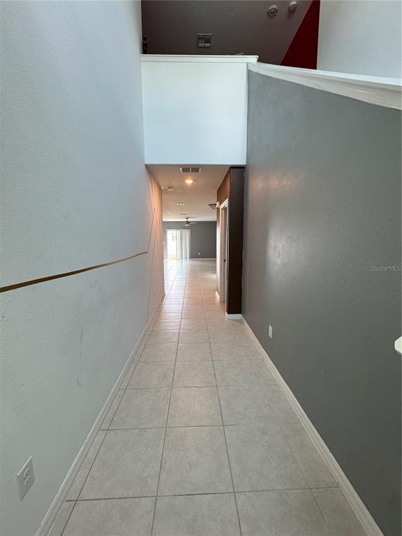 A long hallway with light-colored tile flooring leads toward an open living area — 36569 SMITHFIELD LANE, ZEPHYRHILLS, FL