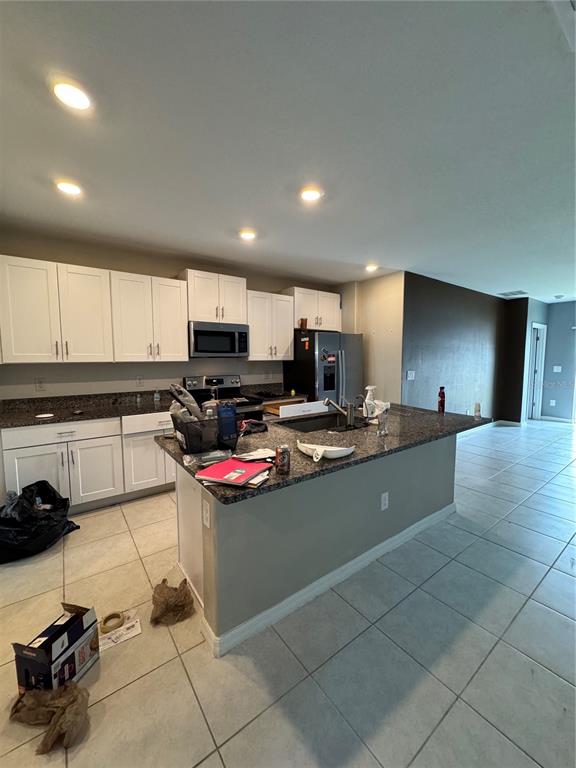 A kitchen features white cabinets, granite countertops, a central island, and tile flooring — 36569 SMITHFIELD LANE, ZEPHYRHILLS, FL
