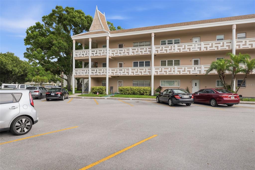 A three-story apartment building with a parking lot in the foreground — 2435 SUMATRAN WAY UNIT 23, CLEARWATER, FL