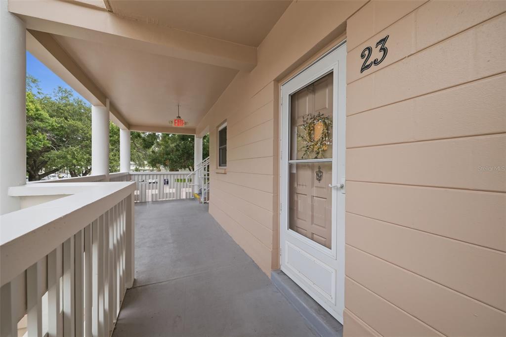 A covered outdoor walkway leads to a white door marked with the number 23 — 2435 SUMATRAN WAY UNIT 23, CLEARWATER, FL