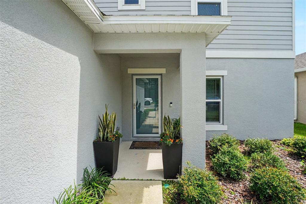 The exterior view shows a covered entryway with a glass front door and potted plants — 2051 ROSEWOOD CIRCLE, LAKELAND, FL
