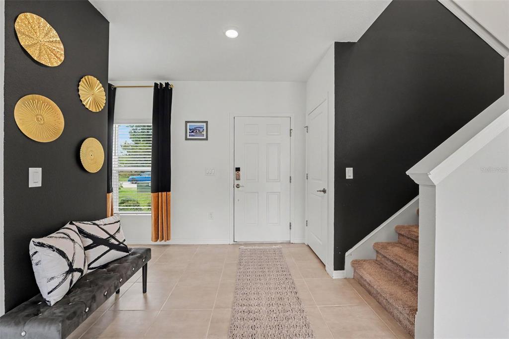 An entryway features a black accent wall, a bench, a staircase, and a front door — 2051 ROSEWOOD CIRCLE, LAKELAND, FL