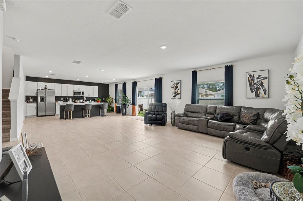 An open-concept living room and kitchen featuring tile flooring, a large sectional, and white cabinetry — 2051 ROSEWOOD CIRCLE, LAKELAND, FL