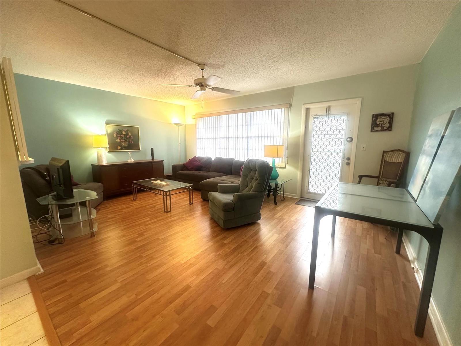 A living room features light blue walls, wood flooring, a ceiling fan, and a glass-topped table — 162 Grantham E # 162, Deerfield Beach FL 33442, DEERFIELD BEACH, FL