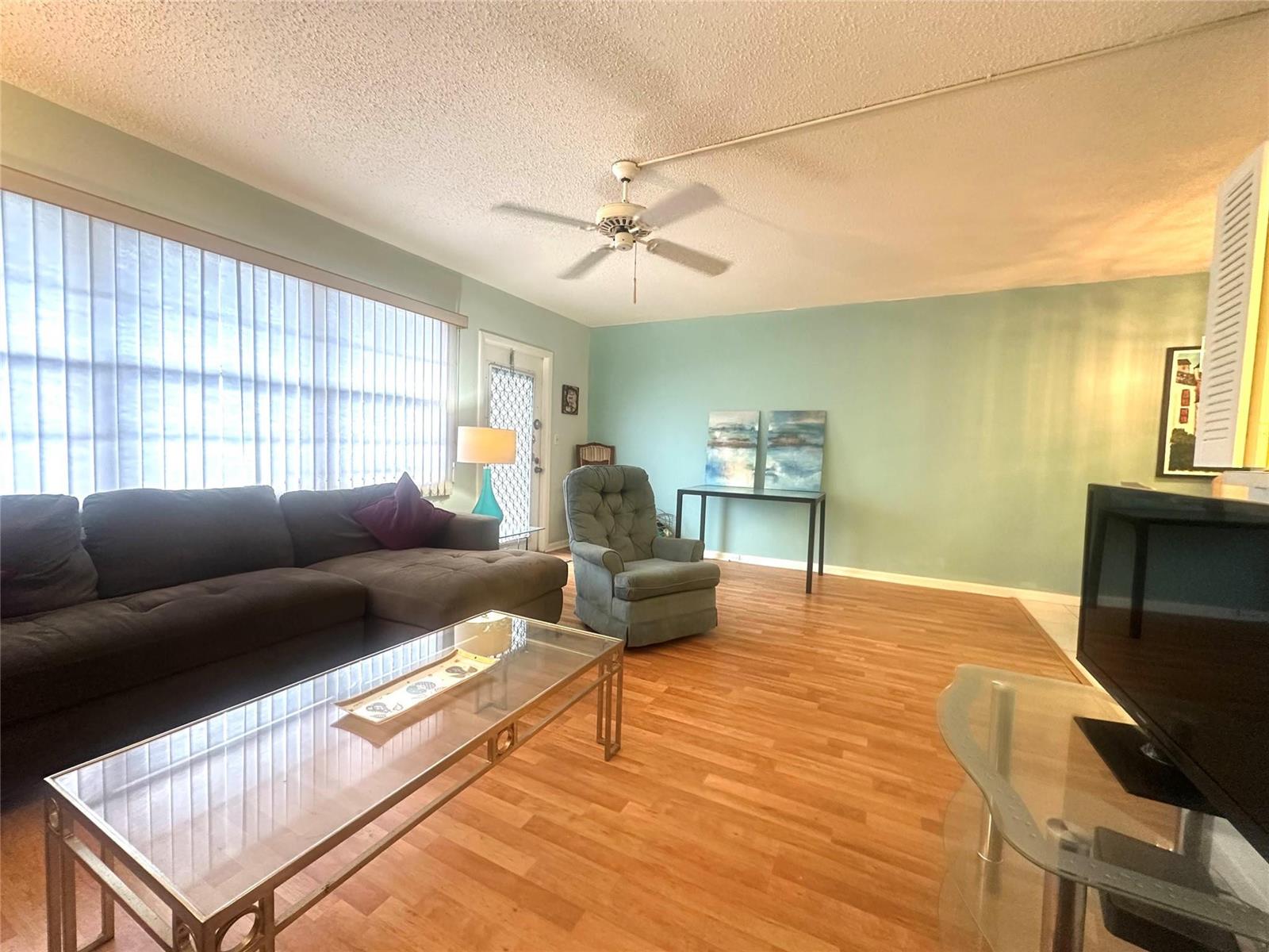 A living room features a dark sectional sofa, a glass coffee table, and light green walls — 162 Grantham E # 162, Deerfield Beach FL 33442, DEERFIELD BEACH, FL