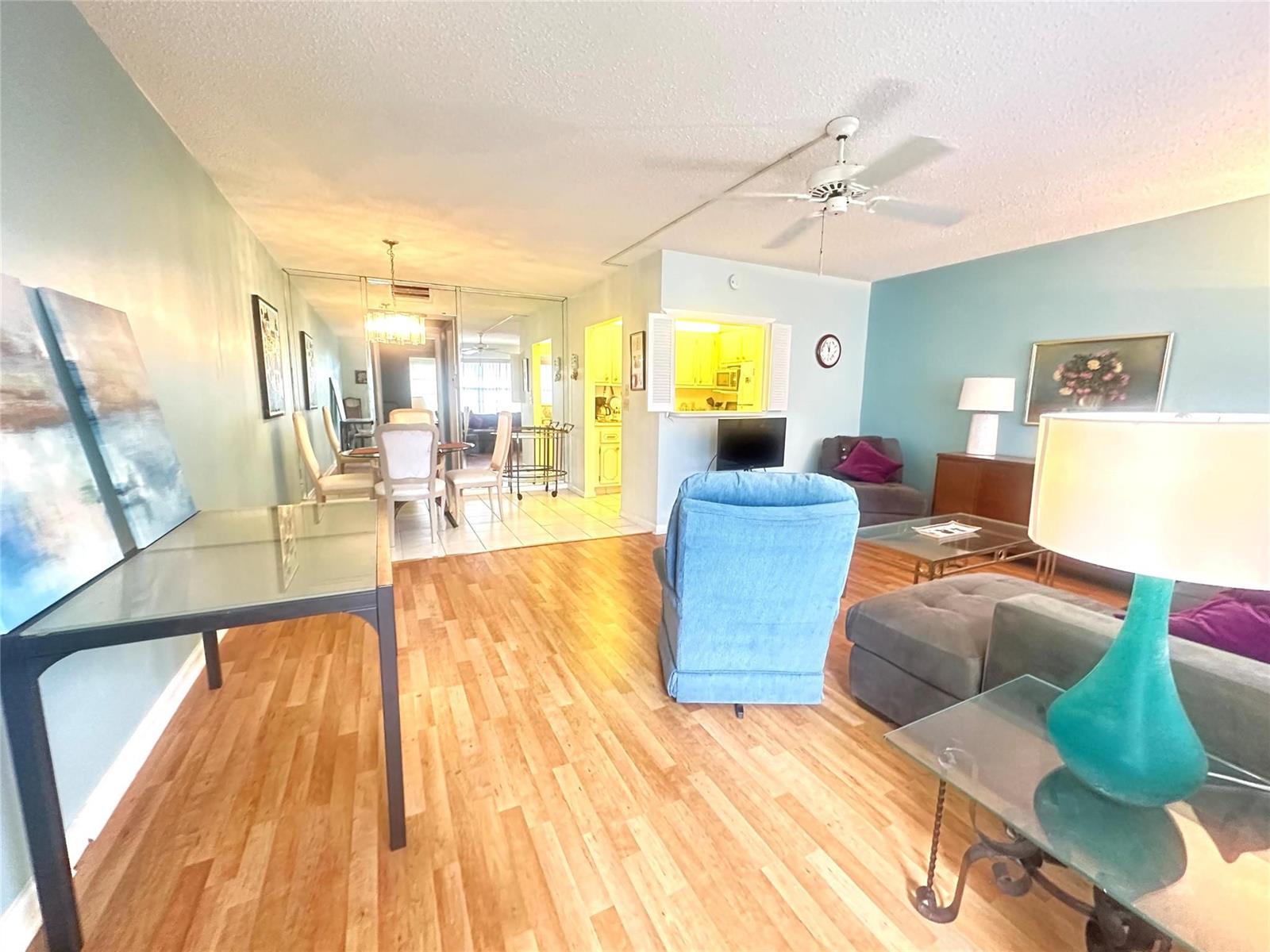 A living and dining area features light wood flooring, blue walls, and a ceiling fan — 162 Grantham E # 162, Deerfield Beach FL 33442, DEERFIELD BEACH, FL
