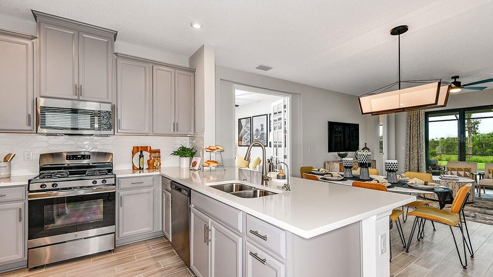 A kitchen with gray cabinets, stainless steel appliances, and a central island with a sink — 825 STEEL DRIVE, APOLLO BEACH, FL