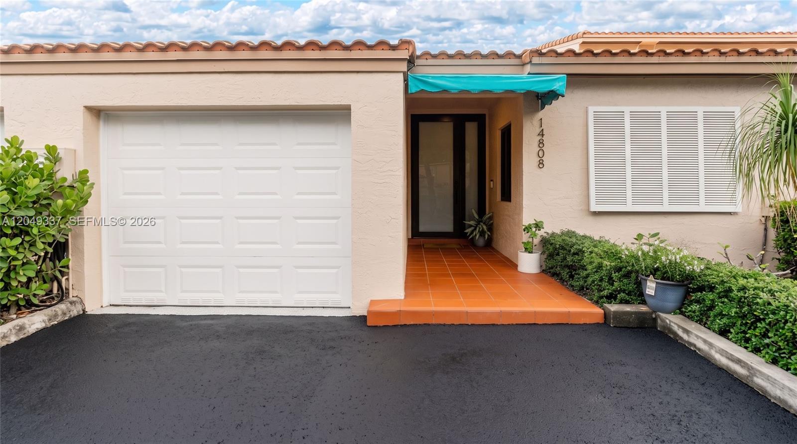The exterior view shows a house with a white garage door and a tiled entryway — 14808 Balgowan Rd, Miami Lakes FL 33016, MIAMI LAKES, FL